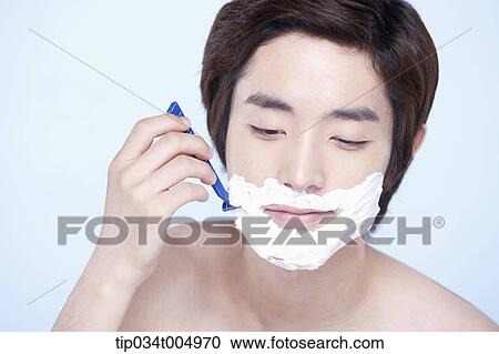 Stock Image - a topless man smiling while shaving. Fotosearch