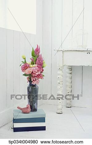 Stock Image - a vase with flowers on a pile of books. Fotosearch
