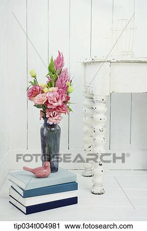 Stock Image - a vase with flowers on a pile of books. Fotosearch