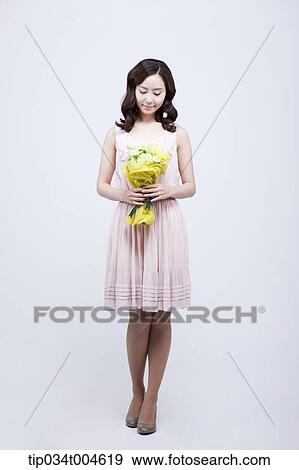 Stock Photo - A woman holding a flower bouquet in her hands . Fotosearch
