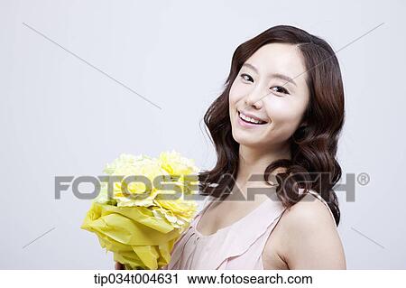 A woman holding a flower bouquet smiling at camera View Large Photo Image Stock Image - A woman holding a flower bouquet smiling at camera. Fotosearch