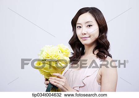 A woman holding a flower bouquet looking at camera View Large Photo Image Stock Image - A woman holding a flower bouquet looking at camera. Fotosearch