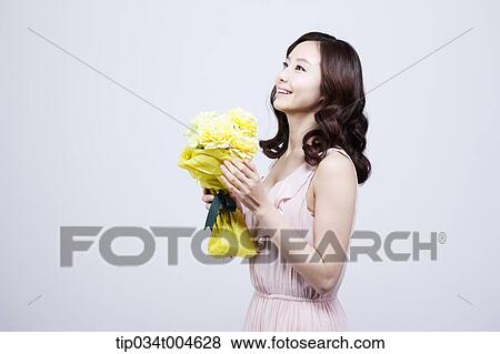 Stock Photo - A woman holding a flower bouquet . Fotosearch