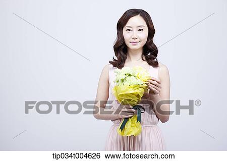 Stock Photograph - A woman holding a flower bouquet . Fotosearch