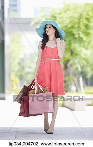 A woman in a dress and hat walking with many shopping bags View Large Photo Image Stock Image - A woman in a dress and hat walking with many shopping bags. Fotosearch