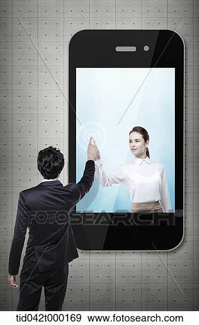 Stock Photo - a woman in a mobile phone pointing same place as a man outside a mobile phone . Fotosearch