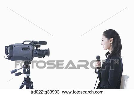a woman in black suit sitting on a chair with microphone in front of a studio camera View Large Photo Image Stock Image - a woman in black suit sitting on a chair with microphone in front of a studio camera . Fotosearch