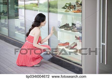 Stock Image - A woman in coral dress and turquoise hat posing in a city. Fotosearch