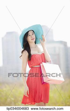 A woman in coral dress and turquoise hat holding a shopping bags View Large Photo Image Stock Image - A woman in coral dress and turquoise hat holding a shopping bags. Fotosearch