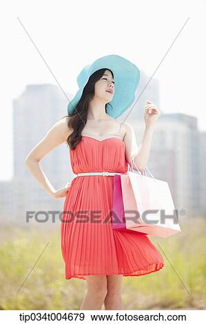 A woman in coral dress and turquoise hat holding a shopping bag View Large Photo Image Stock Photo - A woman in coral dress and turquoise hat holding a shopping bag . Fotosearch