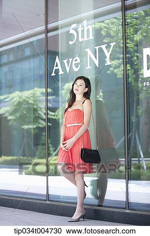 a woman in coral dress standing in front of a show window with a 7th Ave NY sign View Large Photo Image Stock Image - a woman in coral dress standing in front of a show window with a 7th Ave NY sign. Fotosearch