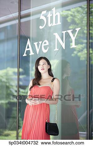 a woman in coral dress standing in front of a show window with a 9th Ave NY sign View Large Photo Image Stock Image - a woman in coral dress standing in front of a show window with a 9th Ave NY sign. Fotosearch
