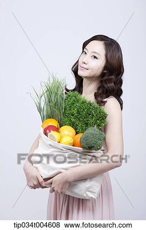A woman in dress holding a bag of vegetables View Large Photo Image Stock Photo - A woman in dress holding a bag of vegetables. Fotosearch
