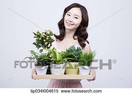 Stock Photography - A woman in dress holding a tray with plants . Fotosearch