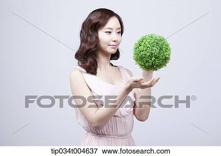 Stock Photo - A woman in dress playing with a ball made from grass. Fotosearch