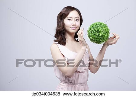 Stock Photo - A woman in dress playing with a ball made from grass. Fotosearch