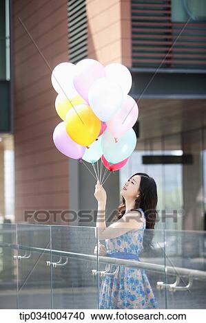 a woman in flower printed outfit looking at a bunch of balloons View Large Photo Image Stock Image - a woman in flower printed outfit looking at a bunch of balloons . Fotosearch