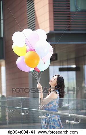 a woman in flower printed outfit looking at a bunch of balloons View Large Photo Image Stock Image - a woman in flower printed outfit looking at a bunch of balloons . Fotosearch