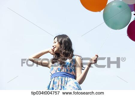 a woman in flower printed outfit holding a bunch of balloons View Large Photo Image Stock Photo - a woman in flower printed outfit holding a bunch of balloons . Fotosearch