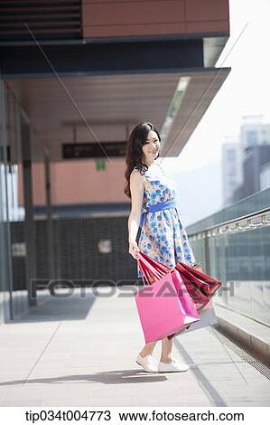 a woman in flower printed outfit with shopping bags turning back View Large Photo Image Stock Image - a woman in flower printed outfit with shopping bags turning back. Fotosearch