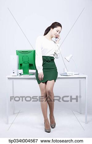 a woman in green skirt answering a phone call View Large Photo Image Stock Photo - a woman in green skirt answering a phone call. Fotosearch