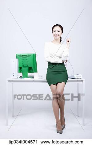 a woman in green skirt leaning on a desk View Large Photo Image Stock Image - a woman in green skirt leaning on a desk. Fotosearch