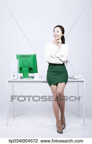 a woman in green skirt leaning on a desk View Large Photo Image Stock Image - a woman in green skirt leaning on a desk. Fotosearch