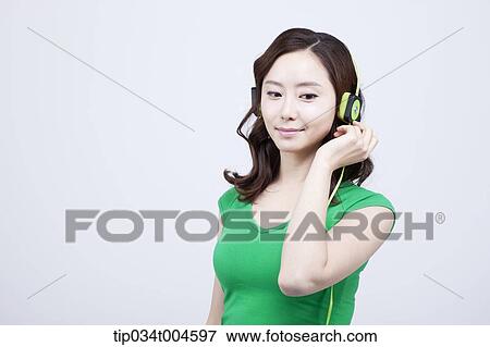 Stock Photo - A woman in green T-shirt listening to a music. Fotosearch