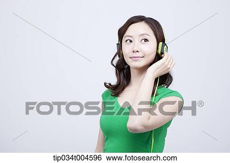 Stock Photograph - A woman in green T-shirt listening to a music. Fotosearch
