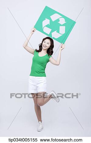 Stock Photography - a woman in green t-shirt posing with a recycling logo signboard . Fotosearch