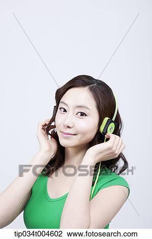 Stock Image - A woman in green T-shirt wearing a green headset. Fotosearch