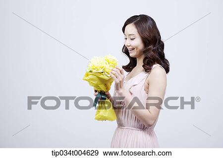 Stock Photo - A woman looking at her flower bouquet . Fotosearch
