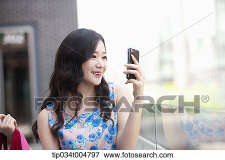 Stock Photo - a woman looking at her mobile phone. Fotosearch