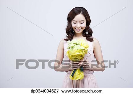 Stock Photo - A woman looking down at her flower bouquet . Fotosearch