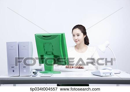 a woman sitting at office desk with a green computer View Large Photo Image Stock Photo - a woman sitting at office desk with a green computer. Fotosearch
