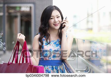 a woman with shopping bags talking on a mobile phone View Large Photo Image Stock Photo - a woman with shopping bags talking on a mobile phone. Fotosearch