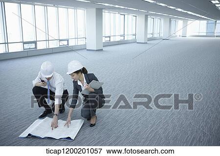 Stock Photo - architect executives discussing with blueprints on the floor of an empty room . Fotosearch