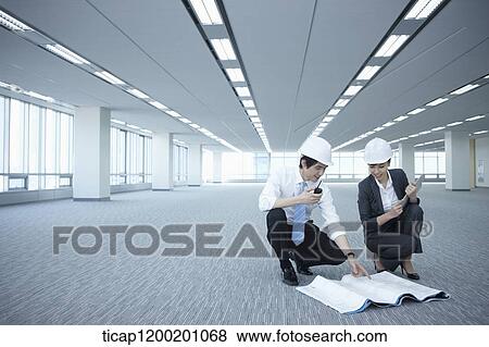 Stock Photo - architect executives discussing with blueprints on the floor of an empty room . Fotosearch