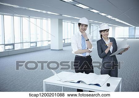 architect executives posing at camera with blueprints on a desk of an empty room View Large Photo Image Stock Photo - architect executives posing at camera with blueprints on a desk of an empty room. Fotosearch
