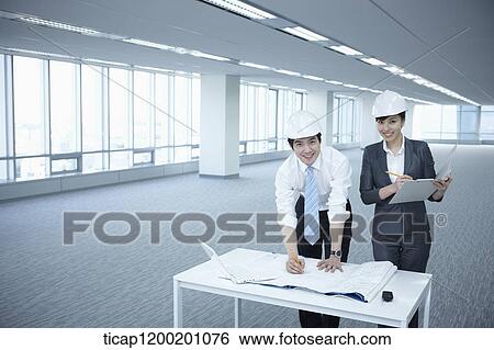 architect executives posing at camera with blueprints on a desk of an empty room View Large Photo Image Stock Photograph - architect executives posing at camera with blueprints on a desk of an empty room. Fotosearch