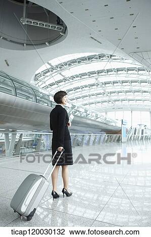 Stock Image - back of a businesswoman walking with luggage in Incheon airport. Fotosearch