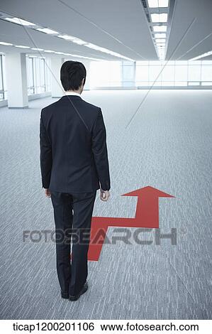 back shot of a businessman standing in front of an arrow in an empty room View Large Photo Image Stock Photograph - back shot of a businessman standing in front of an arrow in an empty room. Fotosearch