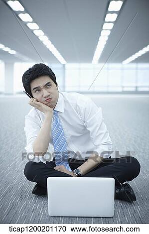 Stock Image - close up of a businessman thinking while using laptop on the floor . Fotosearch