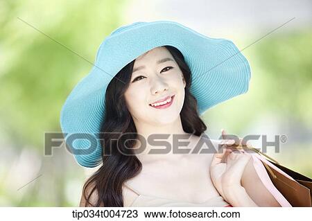 Stock Image - close up shot of a smiling woman in turquoise hat holding shopping bags. Fotosearch