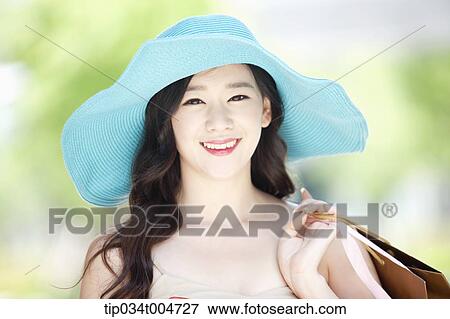 Stock Photo - close up shot of a smiling woman in turquoise hat holding shopping bags. Fotosearch