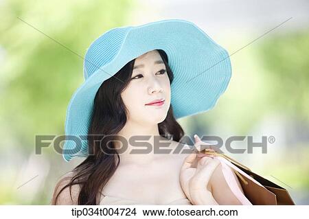 Picture - close up shot of a woman in turquoise hat holding shopping bags. Fotosearch