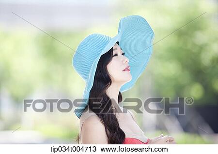 Stock Image - close up shot of a woman in turquoise hat looking sideways. Fotosearch