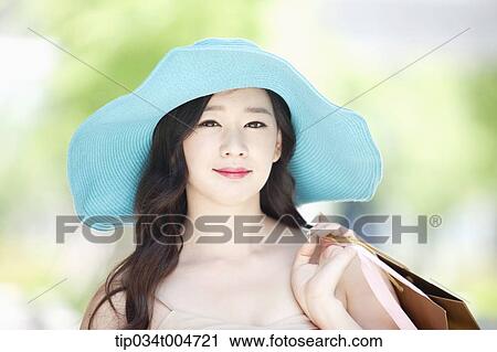 Stock Image - close up shot of a woman in turquoise hat holding shopping bags. Fotosearch