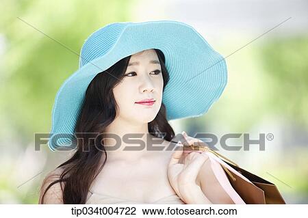 Stock Image - close up shot of a woman in turquoise hat holding shopping bags. Fotosearch