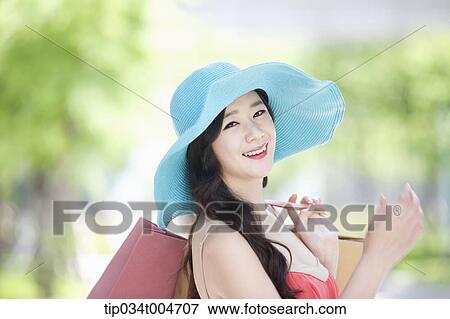 Stock Photo - close up shot of a woman in turquoise hat with shopping bags . Fotosearch